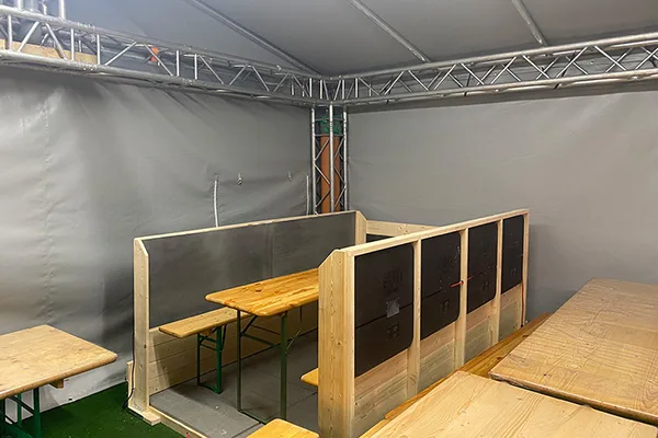Bierzeltgarnitur mit Holzpaneelen, umgeben von schützender Verkleidung und Heizelementen in Rückenhöhe und im Fußbereich