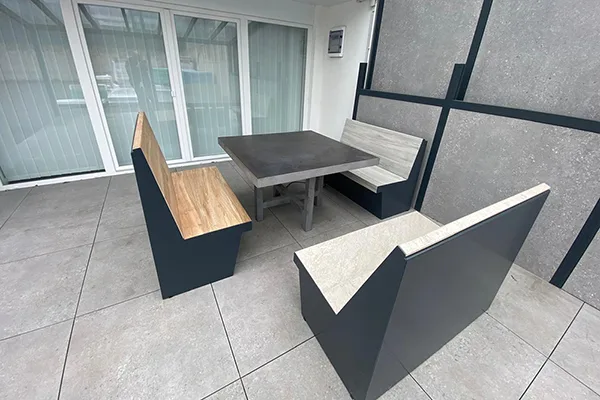 Outdoor-Sitzgruppe mit einem Tisch und drei Bänken, ausgestattet mit beheizbaren Tisch-, Sitz- und Rückenflächen, auf einer Terrasse platziert.