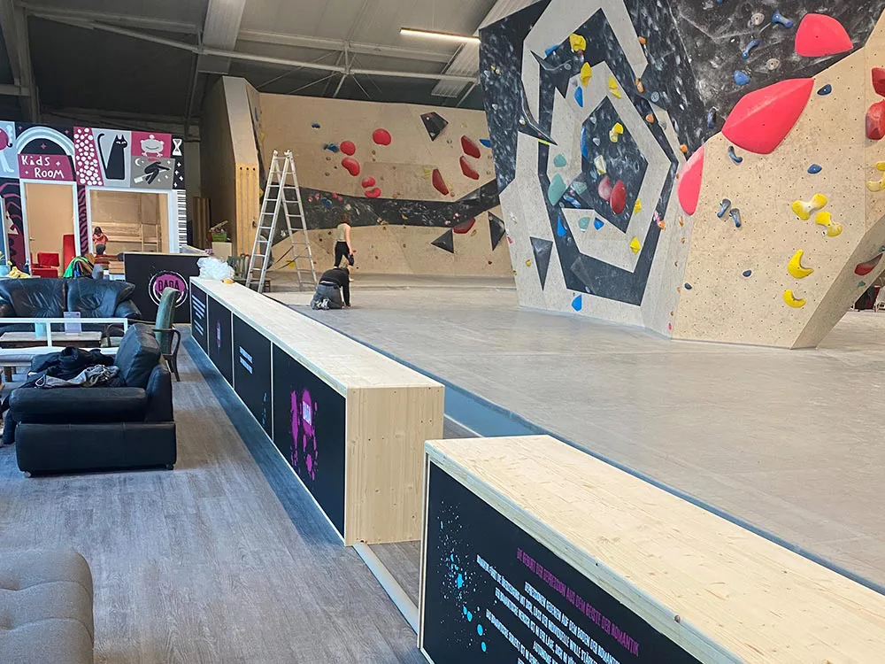 Sitzecke in einer Boulderhalle, an den Fensterfronten und den Raumtrennern befinden sich im unteren Bereich eliTile Großflächenheizungen. Diese können individuell bedruckt werden.